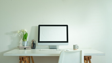 Front view of blank computer monitor on white table in home office, for graphic display montage.
