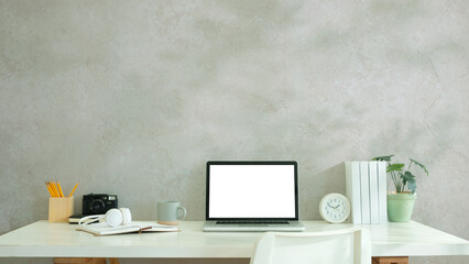 Comfortable home office. Laptop computer, stationery and potted plant on white table.