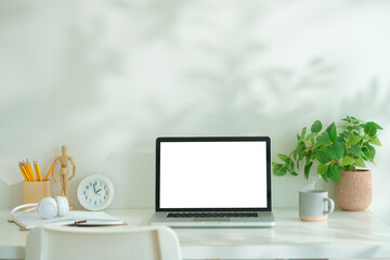 Mockup computer laptop, coffee cup, books and pencil holder on white table.