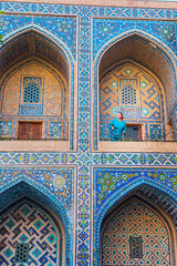 Obraz premium Woman in blue traditional clothing in the courtyard of the Ulugbek Madrassah.