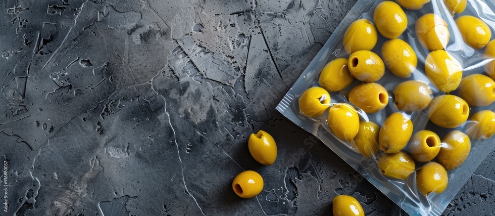 Poster Top view of olives in an unlabeled vacuum pack on a gray stone table with space for text in the image. Creative banner. Copyspace image