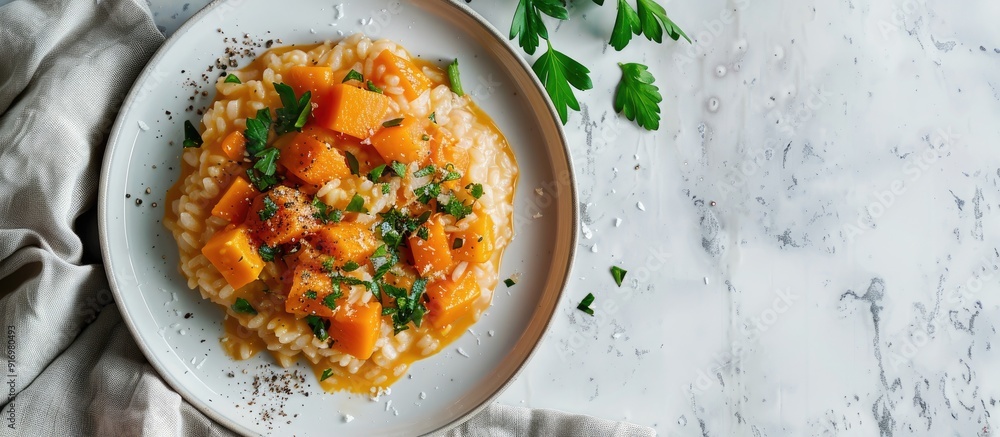 Poster Horizontal image of pumpkin risotto placed on a white table with a contrasting napkin featuring copy space for additional content