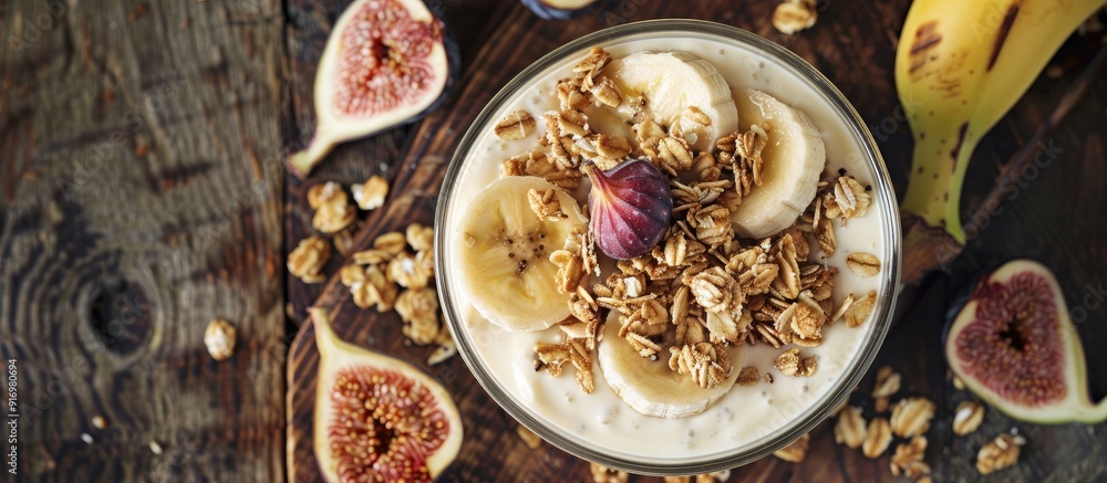 Poster top view of a glass of homemade granola topped with yogurt fresh bananas and figs on a wooden surfac