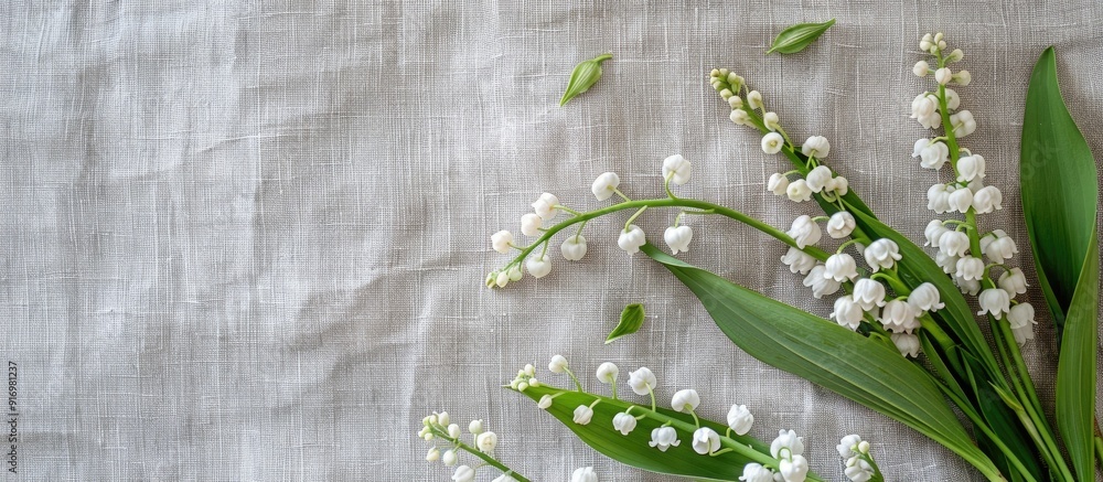 Aufkleber Top view of a rustic greeting card concept with a bouquet of white lilies of the valley and green leaves on a gray linen background offering ample copy space for cover design