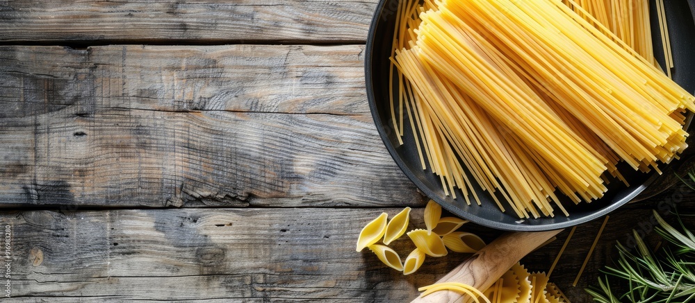 Poster uncooked pasta in a pan on a rustic wooden backdrop showcasing a copy space image