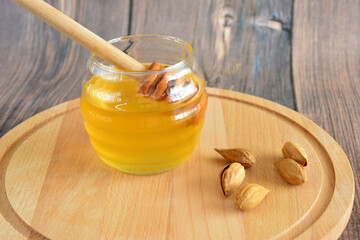 a jar of honey with a wooden stick next to it on the cutting board