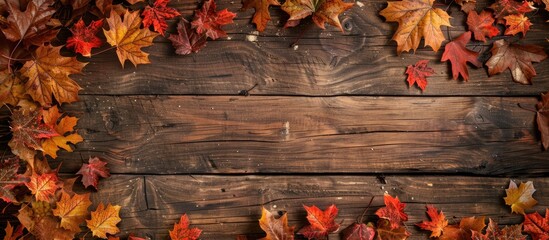 Obraz premium Top view of a vintage wooden table with a frame of autumn leaves on the left side providing a copy space image for your design or product display