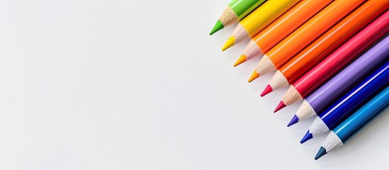 Fototapeta premium Colorful wooden marker pens are arranged on the top right of the white background creating a flat lay composition with a copy space image