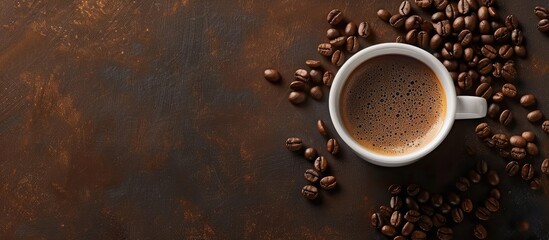 Naklejka premium A tempting freshly brewed cup of coffee with coffee beans shot from above with a spacious copy space image