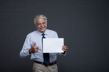 An Elderly Man Holding Aa Blank Piece Of Paper Making The Thumbs-Up Sign