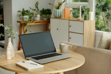 Workplace with laptop on coffee table for online work in the room