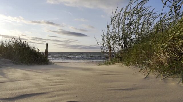 Morze Bałtyckie, zachodząca słońce i pusta piaszczysta plaża. 