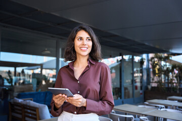 Young latin Hispanic adult professional business woman looking at online trade app. European mature businesswoman CEO holding digital tablet using fintech tab application working in workspace office