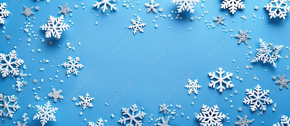 Poster Holiday theme with white snowflakes on a blue backdrop Aerial perspective with a flat layout design and frame for a copy space image