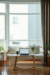 Design living room with sofa and coffee table with laptop on it with big windows in background