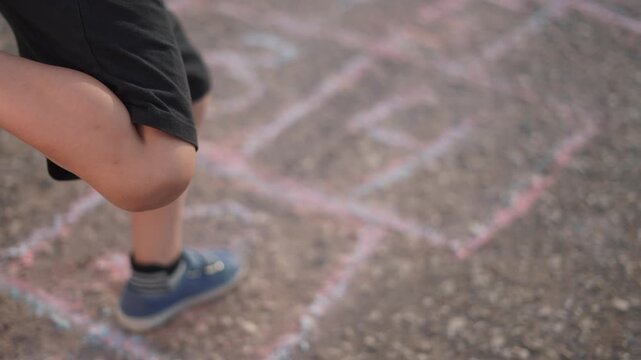 Child is playing game of hopscotch while jumping. happy family kid dream concept. a boy plays hopscotch on asphalt. a boy plays a game of hopscotch while a child jumps on the asphalt lifestyle.
