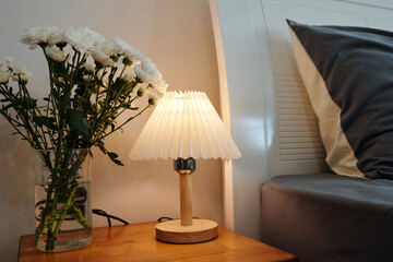 Close-up of bedside table with lamp and bouquet of flowers in bedroom