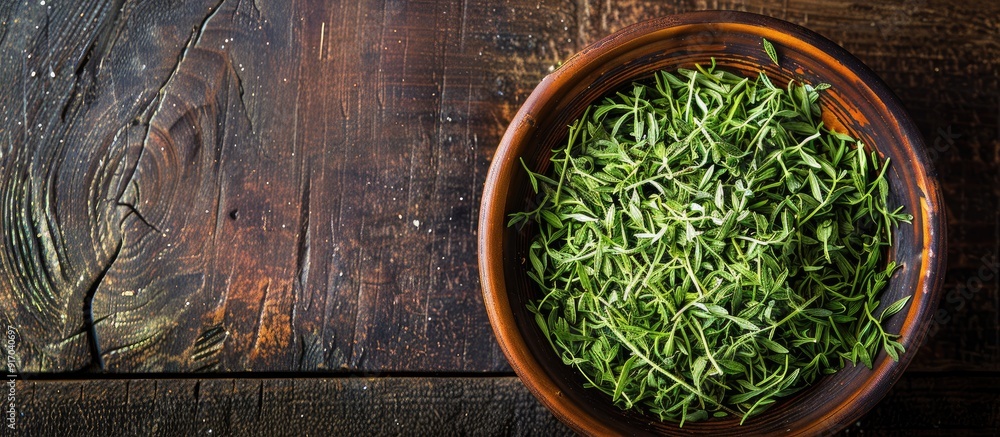 Poster tarragon dried in a bowl on a wooden table with copy space image