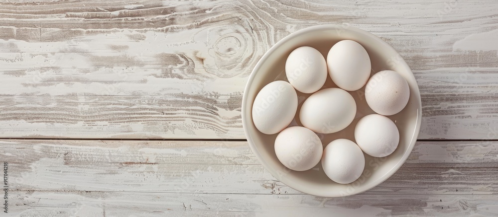 Poster directly above shot of white eggs in bowl on table with ample copy space for a fresh and healthy raw