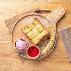 Hot toast topped with icing and jam, banana and cake, a perfect side dish on a wooden tray.