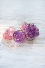 amethyst minerals of druse, pebble and crystal ball close up on wooden background. gemstones for...
