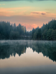 Fototapeta premium Tranquil morning view of Savsat Karagol Black Lake in Artvin, Turkey, with steam rising from the serene forested waters. Savsat Karagol lake is a large trout lake in the forest in Artvin, Turkey