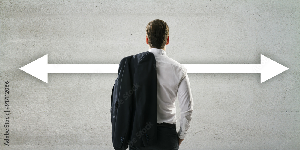 Poster businessman standing in front of arrows pointing left and right on a concrete wall.