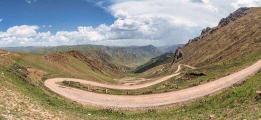 Zigzag serpentine road known as 33 Parrots, leading up to Song Kul Lake, a stunning high alpine...