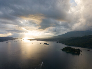 Lit by a peaceful sunset, clouds drift across Lembeh Strait, Indonesia. This body of water, found in North Sulawesi, is a popular destination for scuba diving due to its collection of odd marine life.