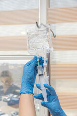 Nurse connecting an IV drip. Nurse preparing and regulating infusion for patient in hospital. Doctor preparing to insert IV needle into patient's arm. Healthcare concept.
