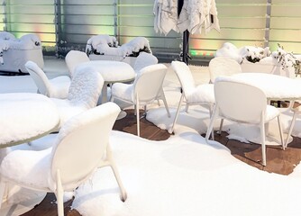 snowy cafe. Tables and chairs are covered with a thick layer of snow. Winter vibe, weather, climate change