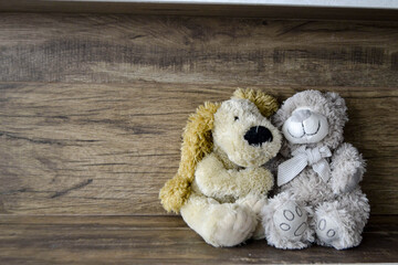 two cute hugging teddy bears, on an old wooden floor