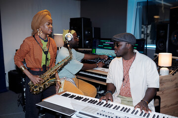 Group of musicians working in recording studio with various instruments Sharing creative process...