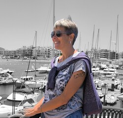 Profile of young,pretty,adult woman,smiling,looking at boats at the port.Girl in profile happy looking at the port.Woman in profile at the port,relaxing,looking at the view.Happy tourist at the port.