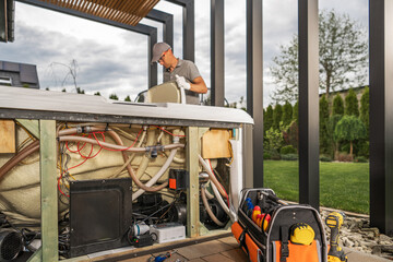 Home SPA Technician Repairing Hot Tub in Backyard on an Overcast Day