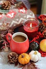 Autumn composition with cup of coffee, autumn leaves, red berries, pumpkins and knitted sweater