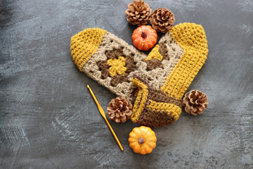 Crocheted sleepers on dark grey background with space for text. Handmade knitted baby booties made of wool. Autumn hobby concept. 