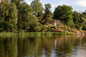 Fototapeta premium Rocky overgrown shore of a lake on a summer evening