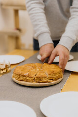 A young man cuts a royal galette at the table.