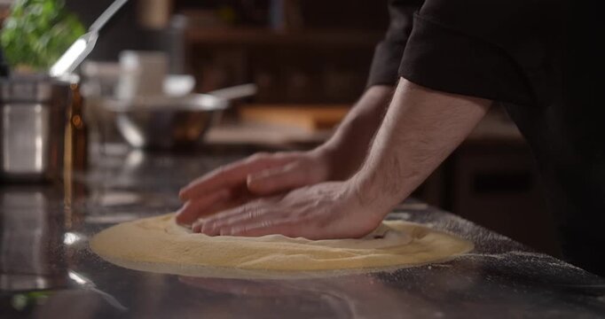 Pizza chef rolls out the pizza dough in restaurant restaurant