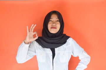 Young cheerful happy smiling pleasant successful employee business woman in her 20s wearing casual brown classic jacket showing okay okay gesture isolated on plain pastel light pink background studio