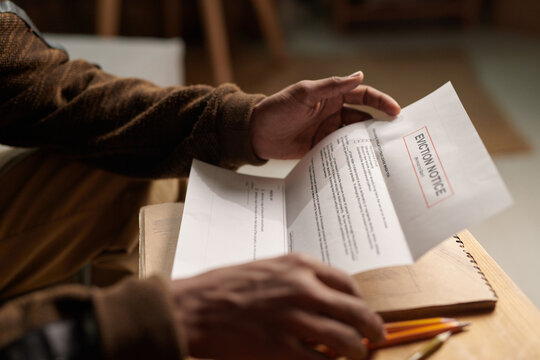 Close-up of person receiving and holding an eviction notice, focusing on their hands and the document with some text visible, creating sense of urgency and concern
