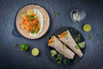 Italian style wrap piada tortilla with cured graved salmon, salad and zucchini served as top view with avocado sour cream dressing dip on a Nordic Design plate