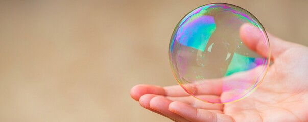 Closeup of a palm softly cupping a small fragile soap bubble the bubbles transparency and the skins texture captured