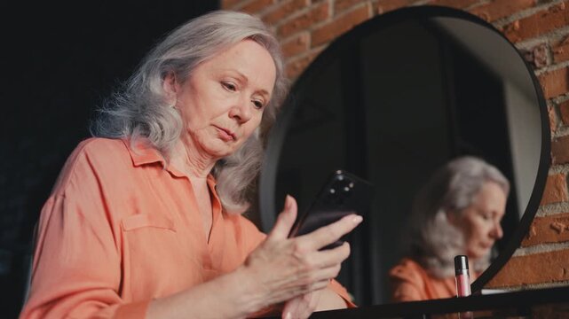 Senior woman hesitating about online purchase on cellphone, discounts, shopping