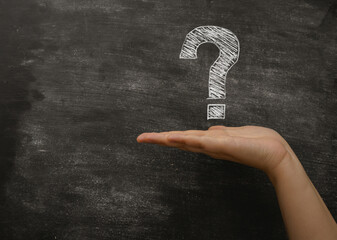 A hand holding a chalkboard with a question mark on it