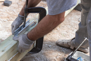 ..Close up view of man with clamp and wood boards. Gluing joinery in the workshop.