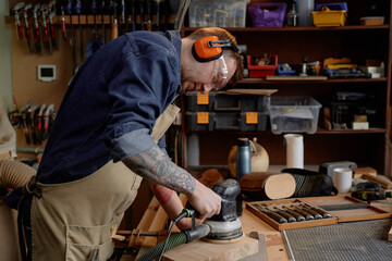 Woodworker wearing protective gear and working on wooden piece with precision, surrounded by...