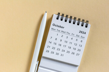 Desk calendar for October 2024 on a beige background.