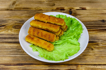Baked fish sticks and lettuce leaves in a plate
